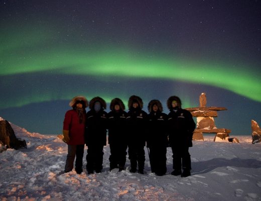 a group of travelers in front of the northern lights in Churchill Manitoba Canada