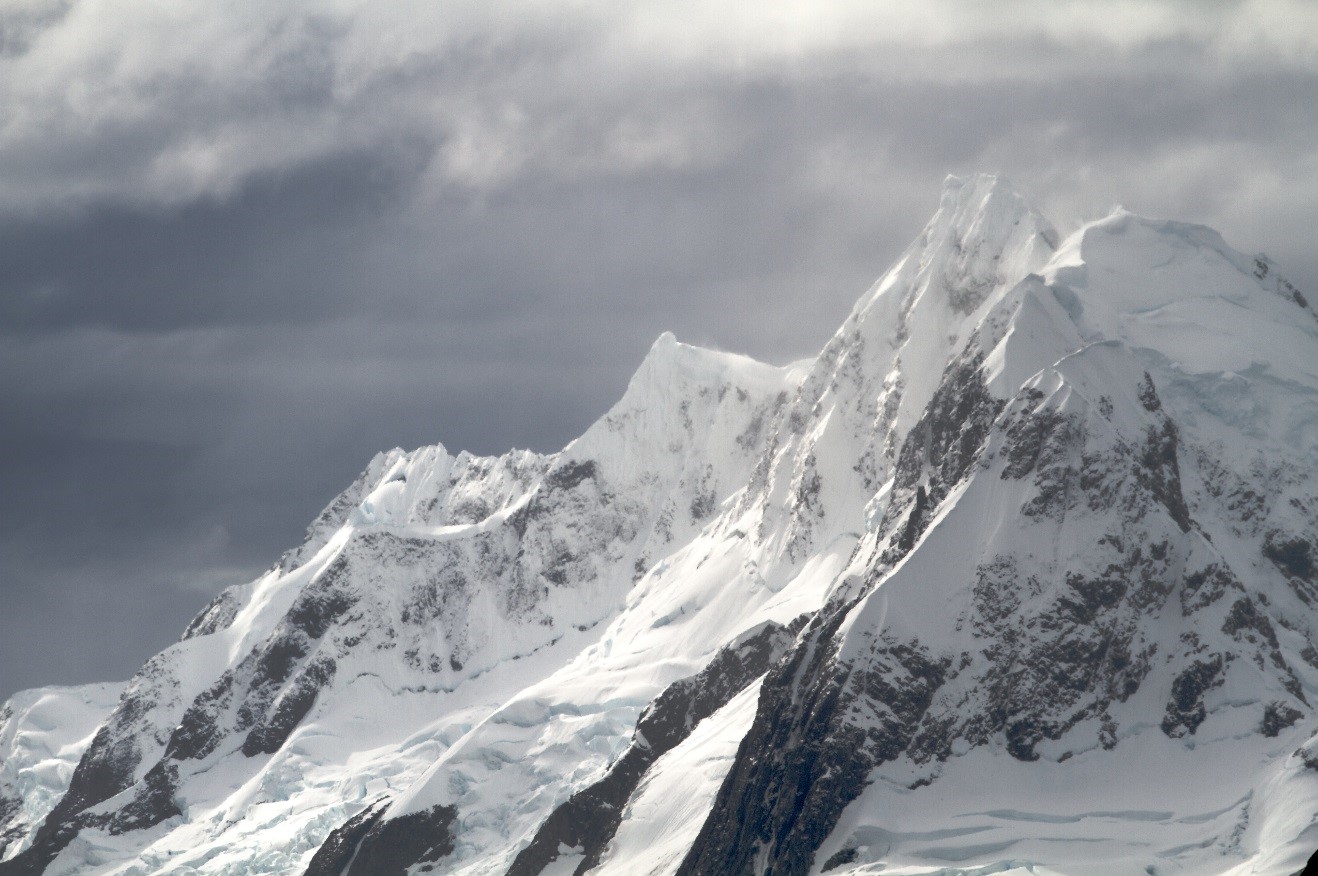 a jagged mountain range in antarctica amidst ominous storm clouds