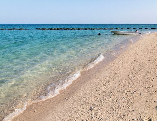a scenic photo of one of borneo's turtle islands with clear water and sandy shore
