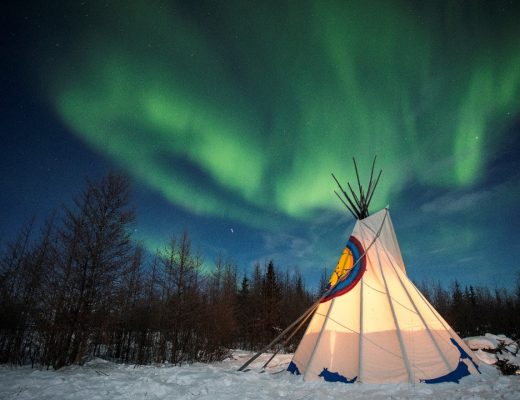 dramatic northern lights swirl over a metis teepee in Churchill Canada