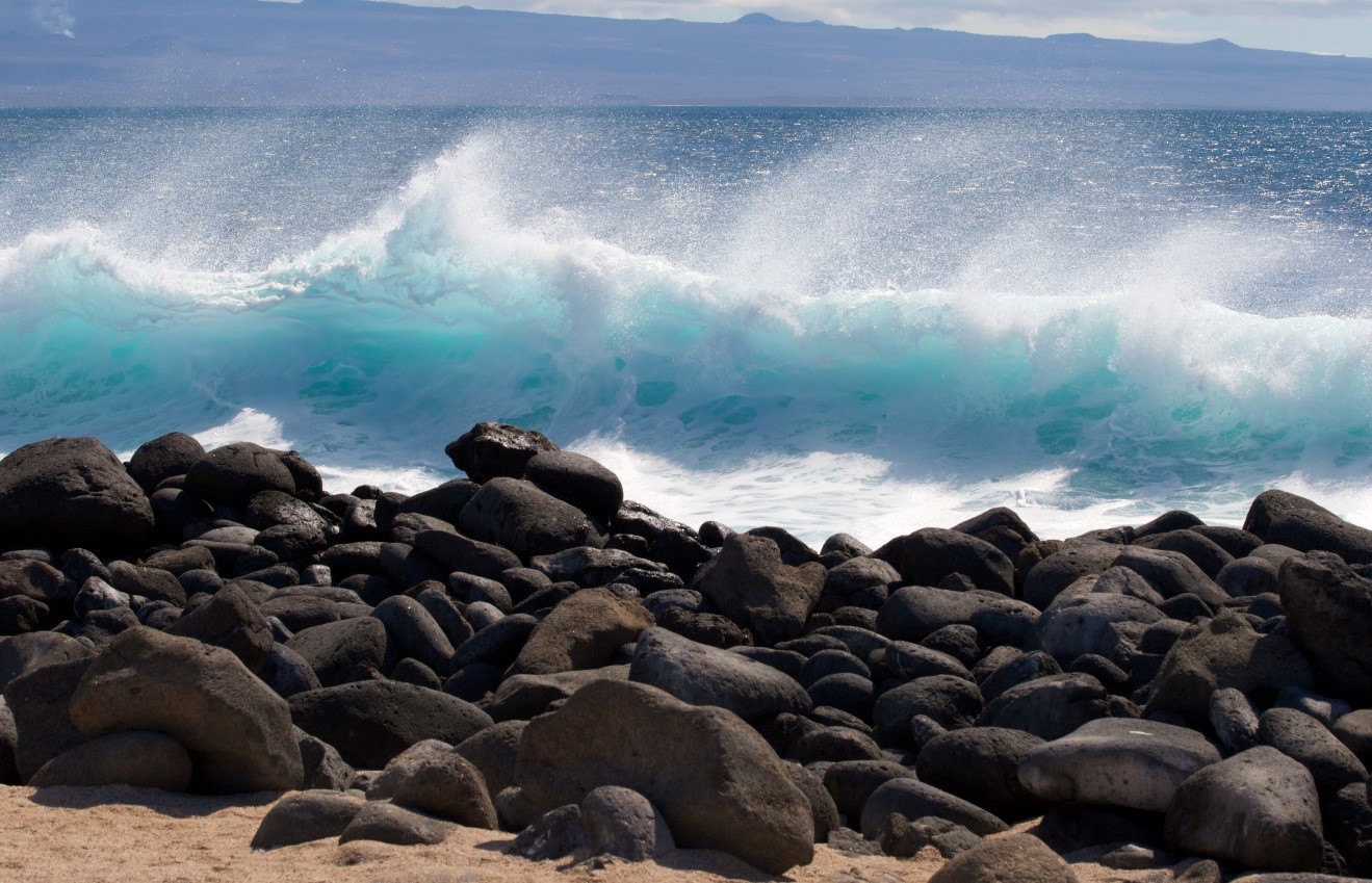 a blue wave crashes on the shore of the galapagos islands