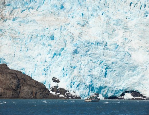 a small boat is at the base of a large glacier in kenai fjords national park