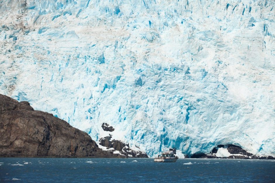 a small boat is at the base of a large glacier in kenai fjords national park