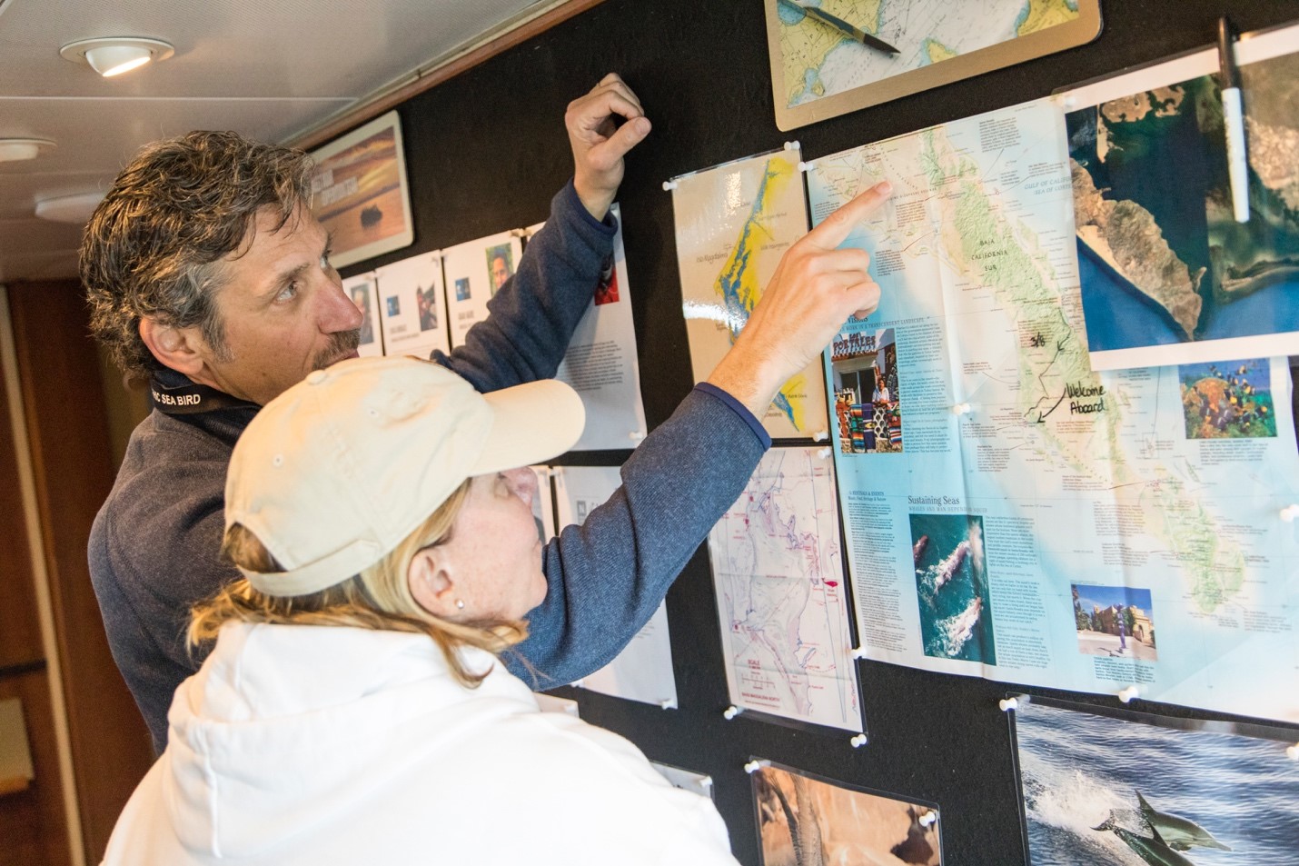 travelers looking at a map on board an expedition vessel in baja