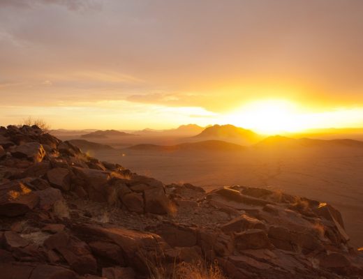 a spectacular sun set shines on the horizon of the namib desert
