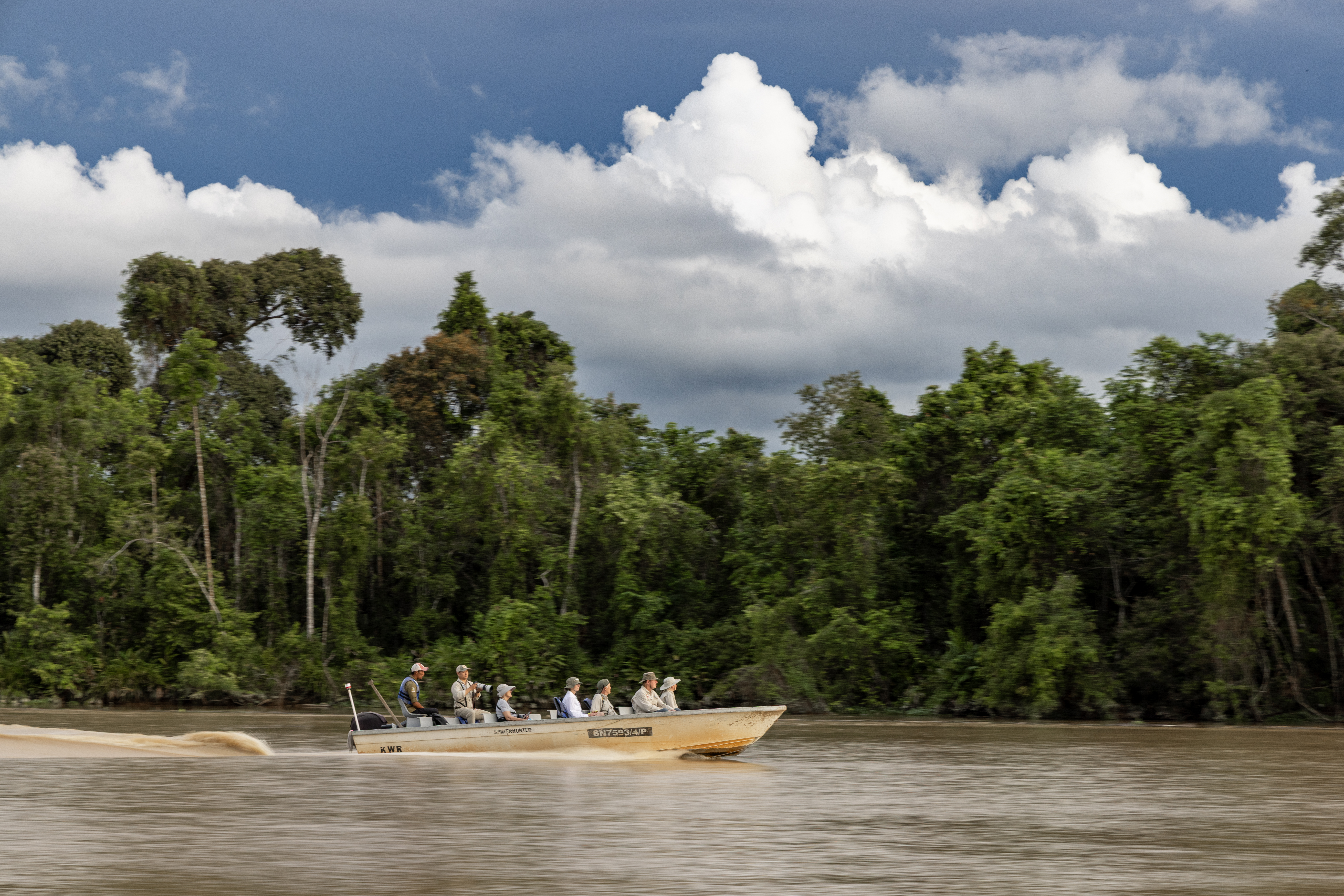 a small skiff motors through the waters of the Kinabatangan
