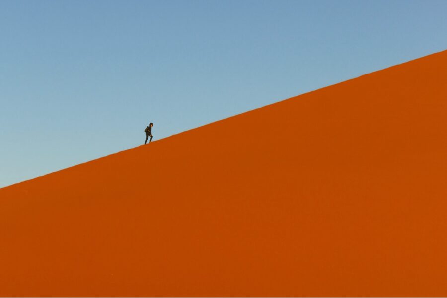 a hiker walks on top of a dune in Namibia