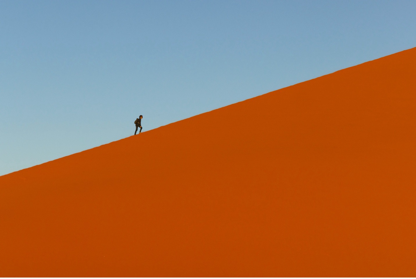 a hiker walks on top of a dune in Namibia